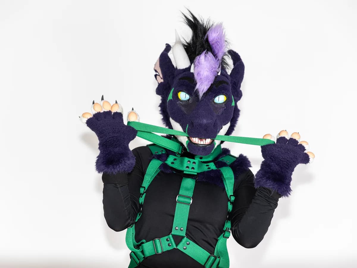 Furry model wearing green harness gear